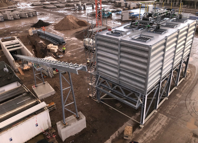 Acht Materialsilos auf einer Baustelle.